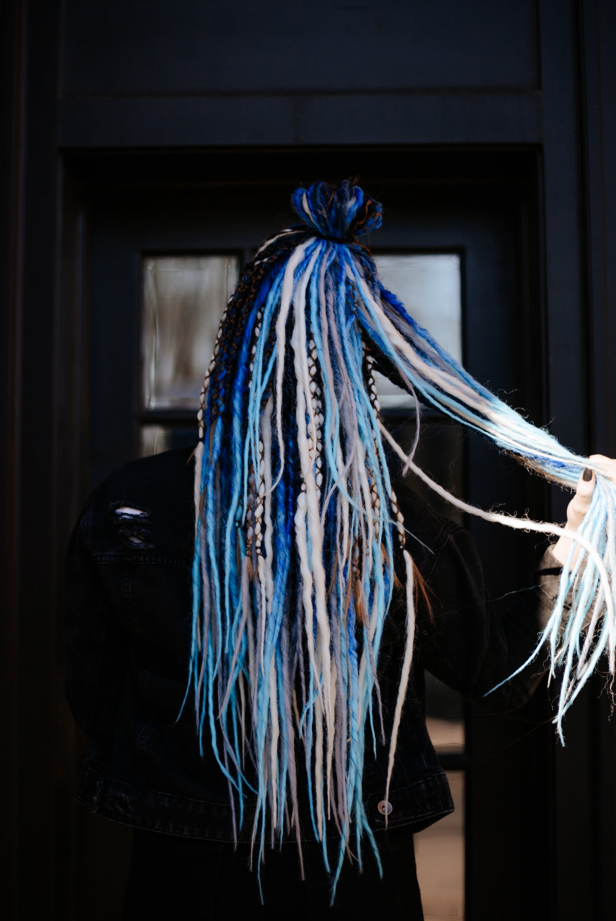 Long dreadlock extensions in bright blue and icy white, held out in the light